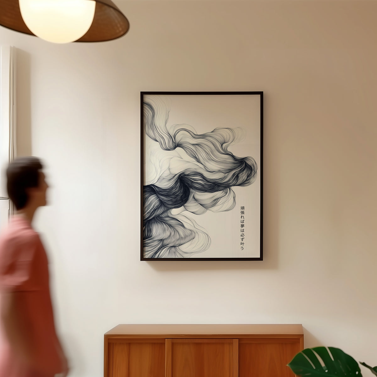 Black ink swirl dreams proverb print in a black frame in a hallway under a rattan pendant