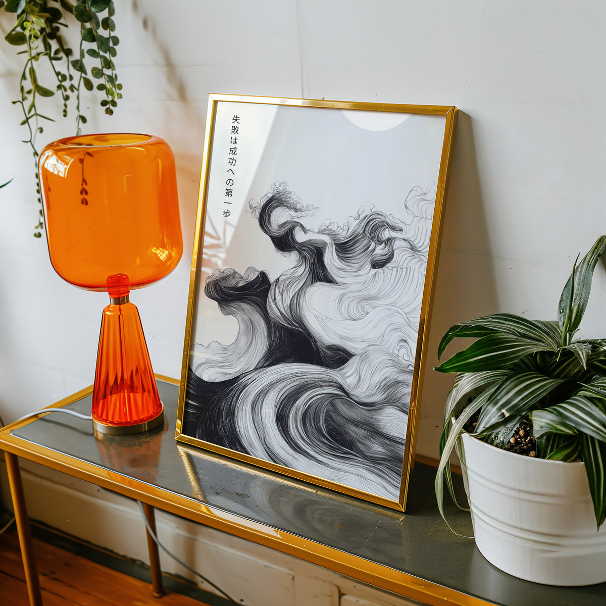 Ink swirl failure and success proverb print shown in a gold frame on a console beside an orange glass lamp