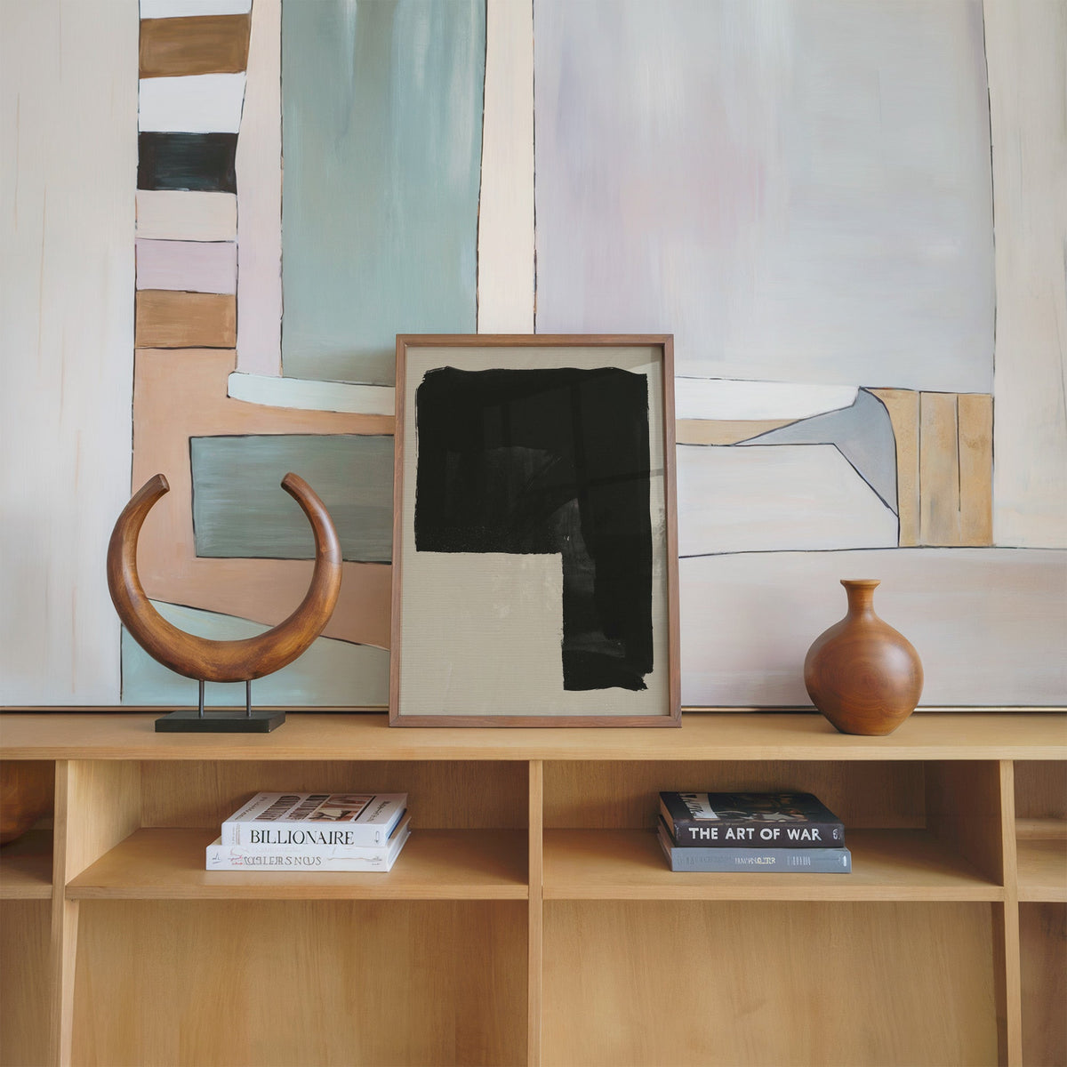 Black inverted L block on greige print in a walnut frame on an oak shelf beside a wooden crescent sculpture