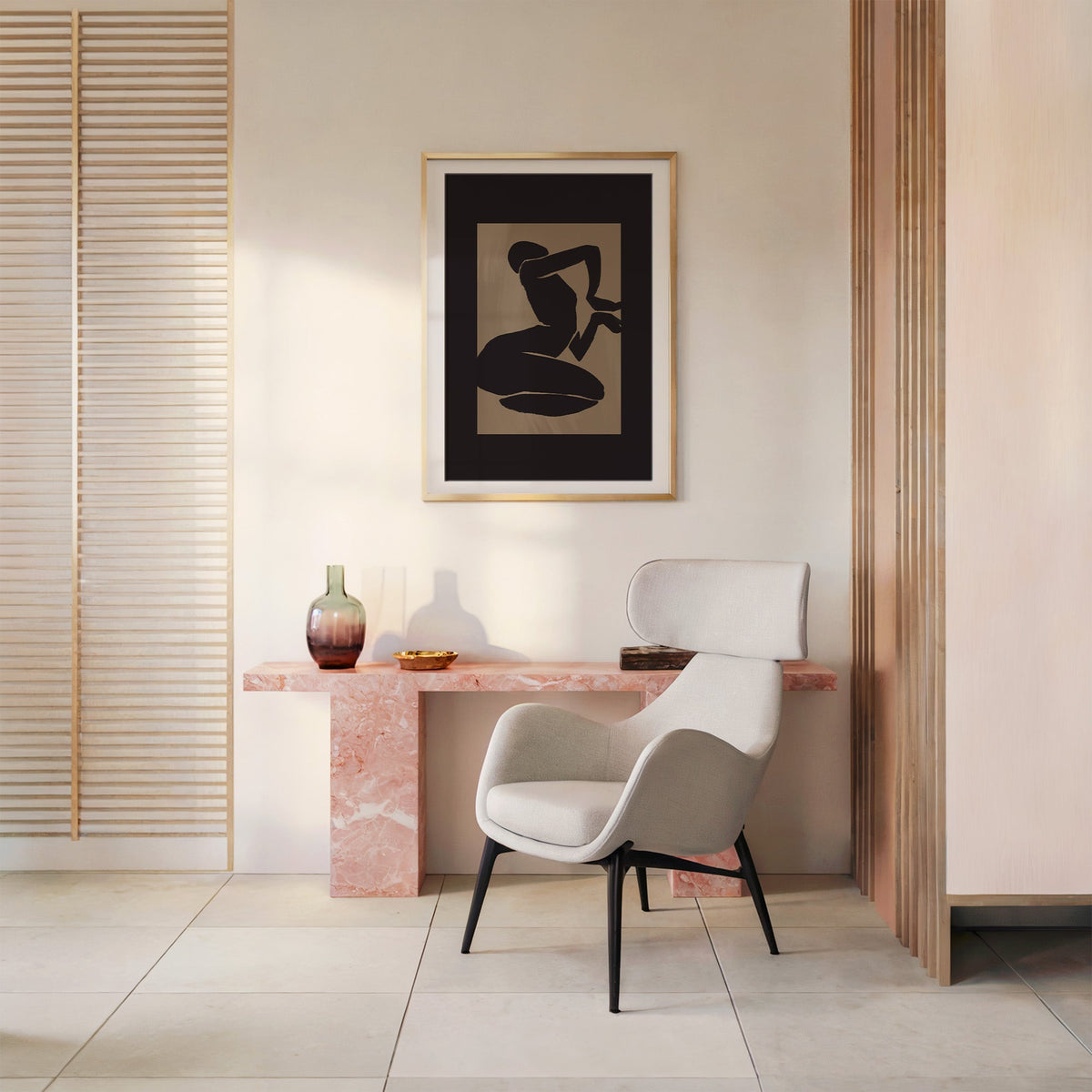 Black kneeling silhouette on taupe panel print shown in a gold frame with a mat above a pink marble console and armchair