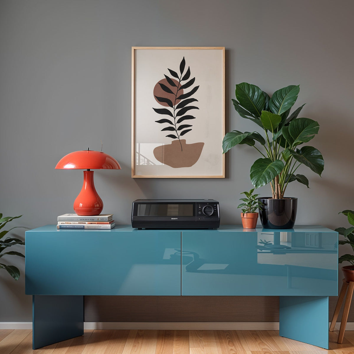 Black leaf branch and terracotta sun boho print in a light oak frame above a teal sideboard with a red mushroom lamp