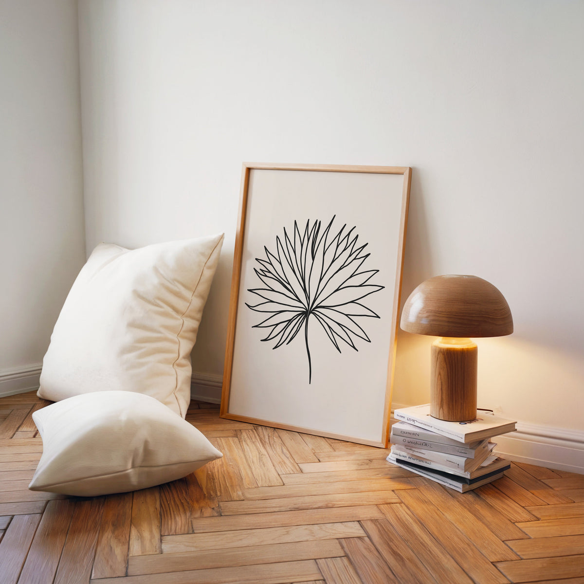 Black line fan leaf minimalist print in a light wood frame on a herringbone floor by a wooden mushroom lamp