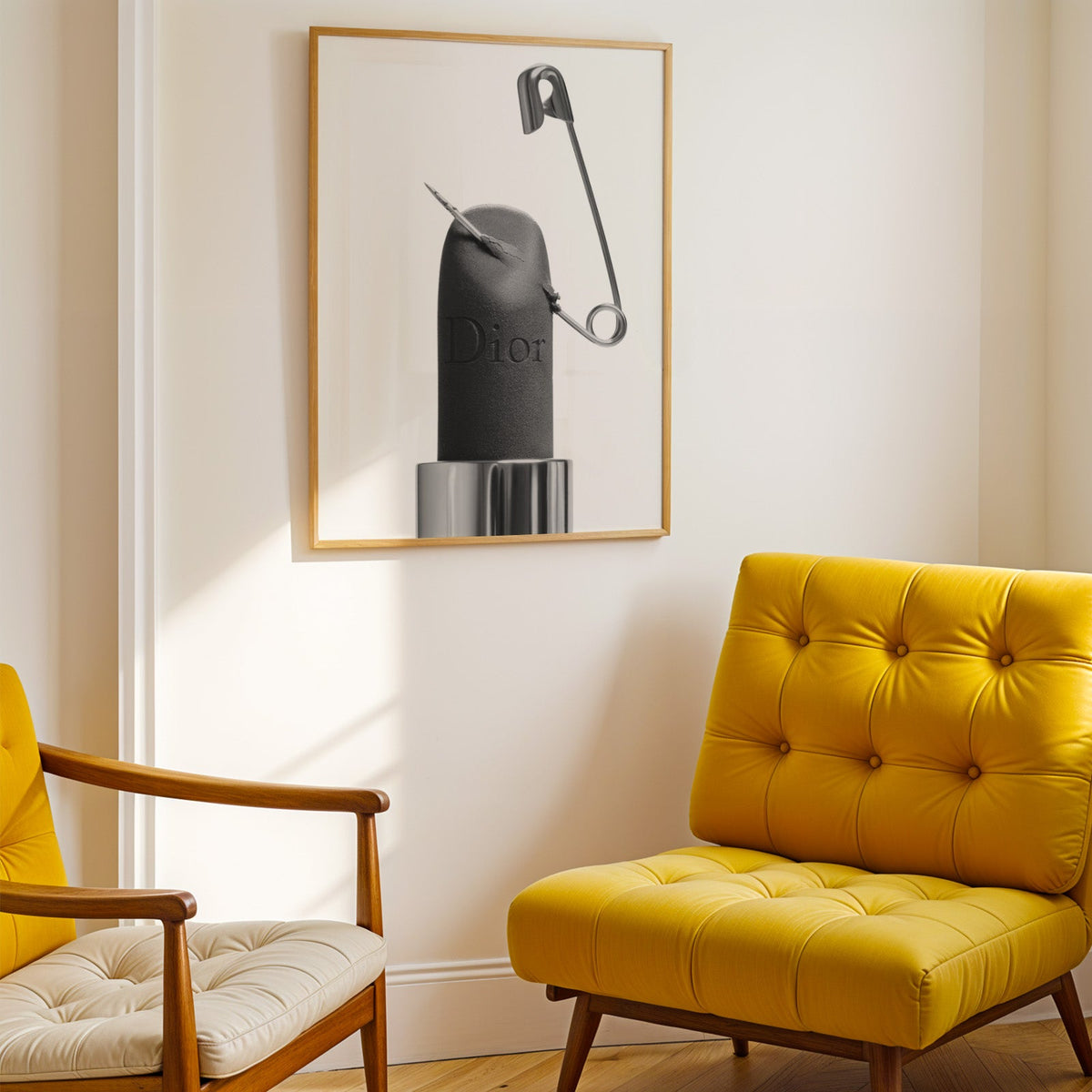 Matte black lipstick pierced by safety pin print shown in a gold frame above a mustard yellow tufted armchair