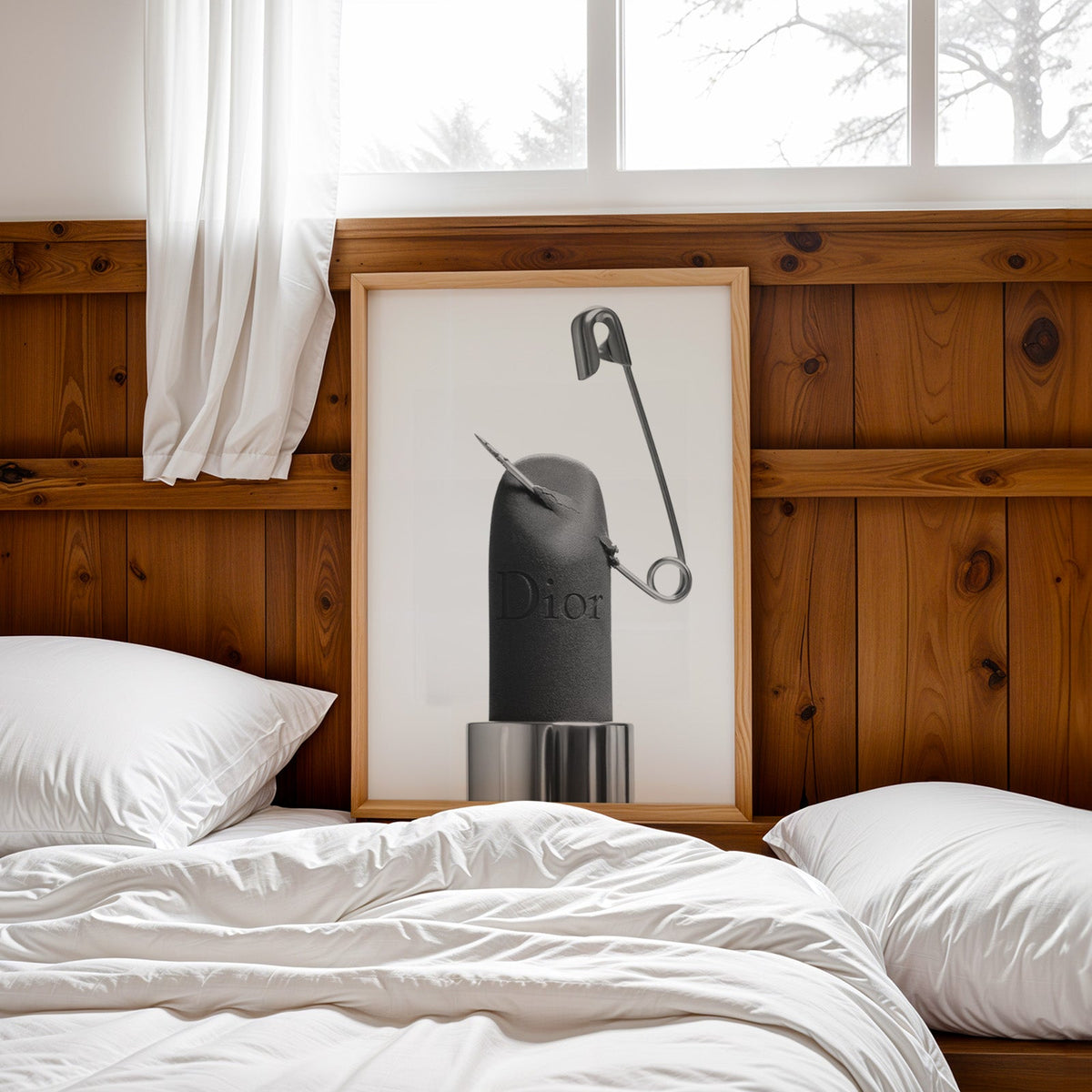 Matte black lipstick pierced by safety pin print in a pine frame leaning on a wood headboard over white bedding