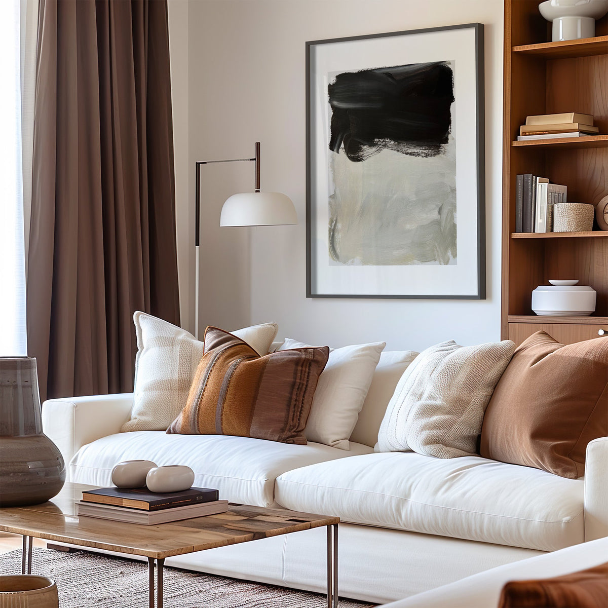 Black over greige brush block print in a black frame above a cream sofa with brown striped pillows