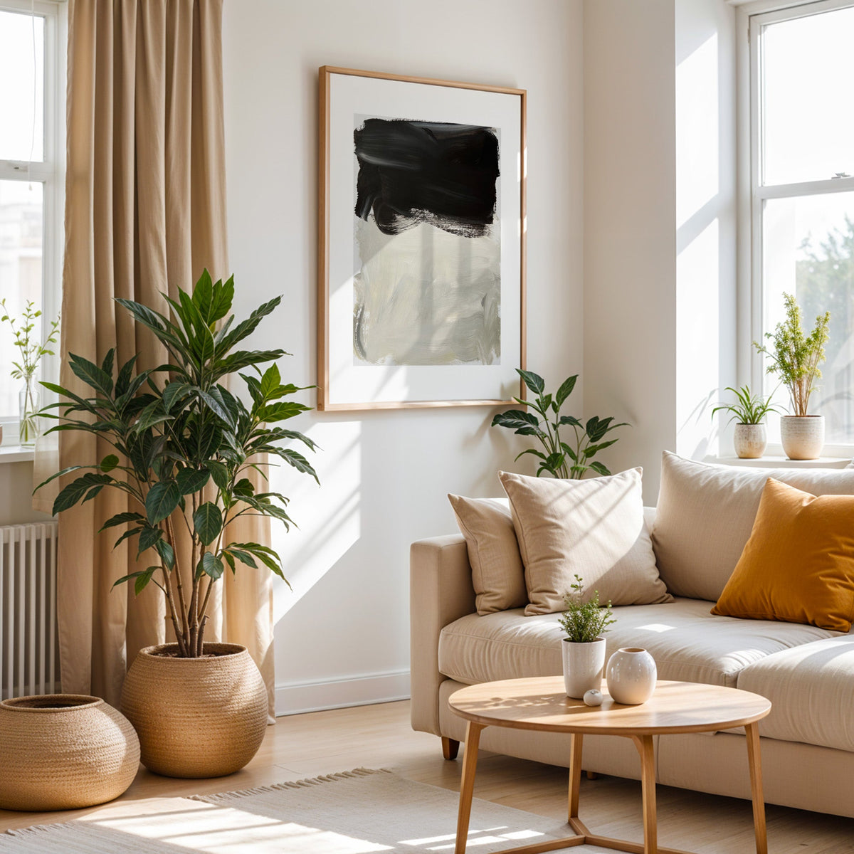 Black over greige brush block print in an oak frame above a cream sofa beside a tall plant in a woven pot