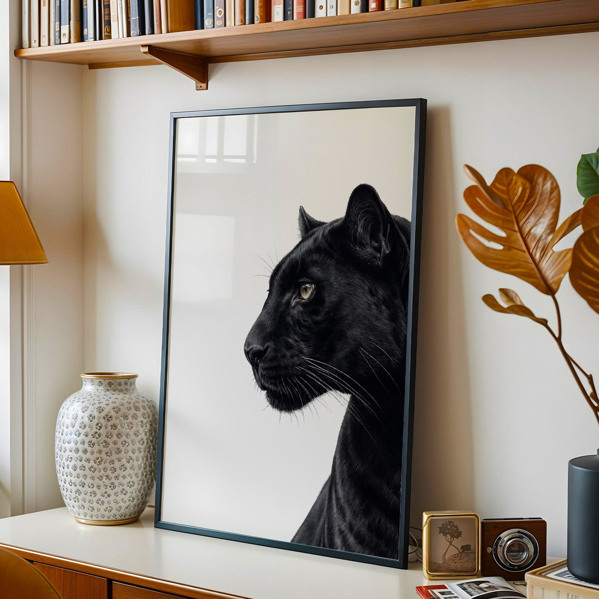 Text-free black panther profile on white background print in a black frame on a console under a bookshelf