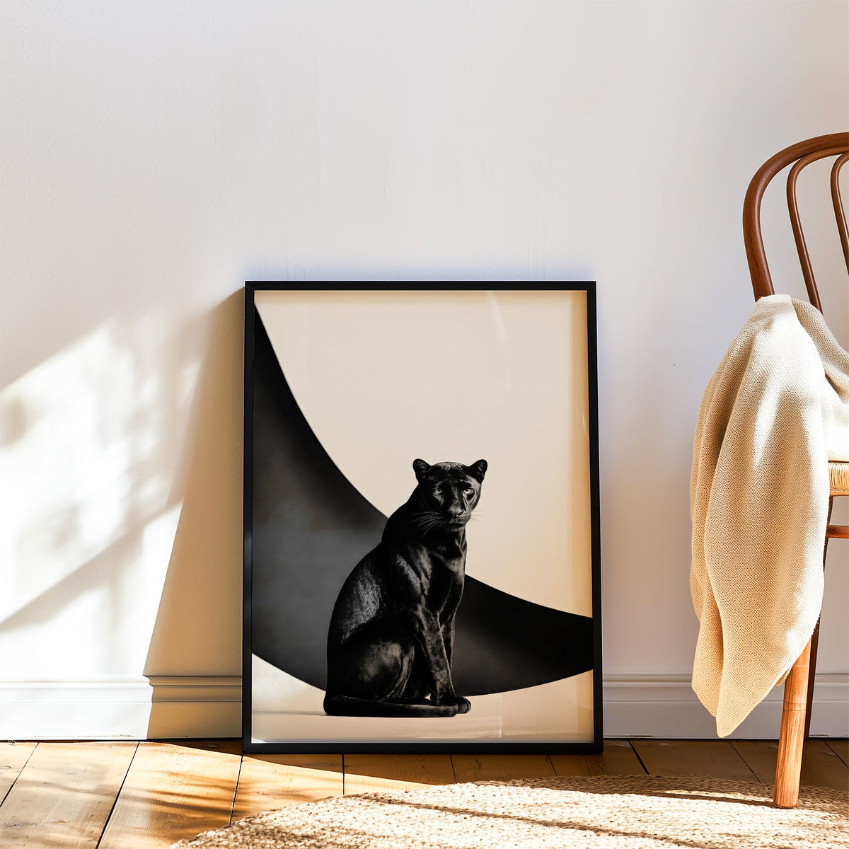 Seated black panther in front of black arc print in a black frame leaning on a wood floor beside a bentwood chair