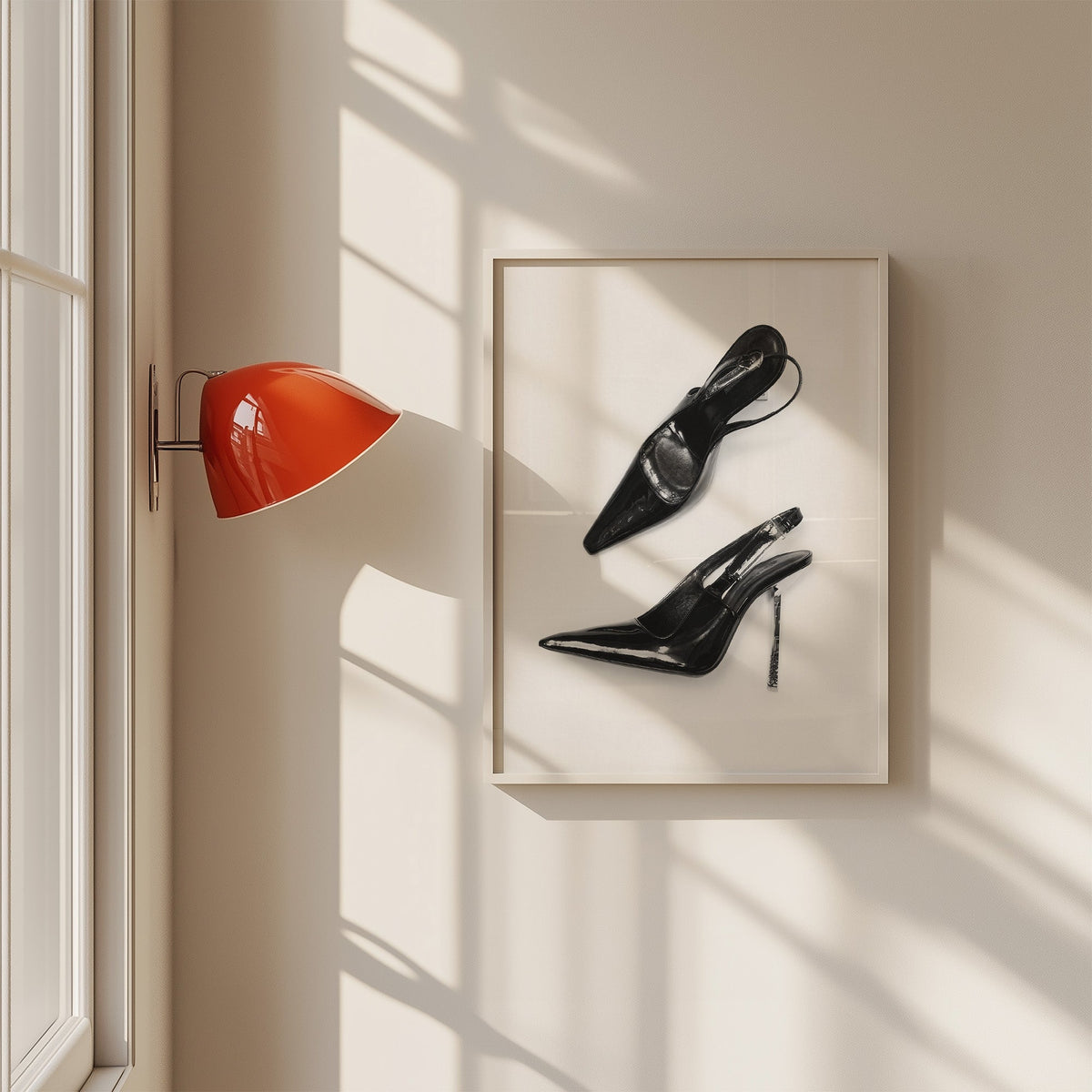Black patent slingbacks with silver heels print in a white frame on a sunlit wall beside a red sconce