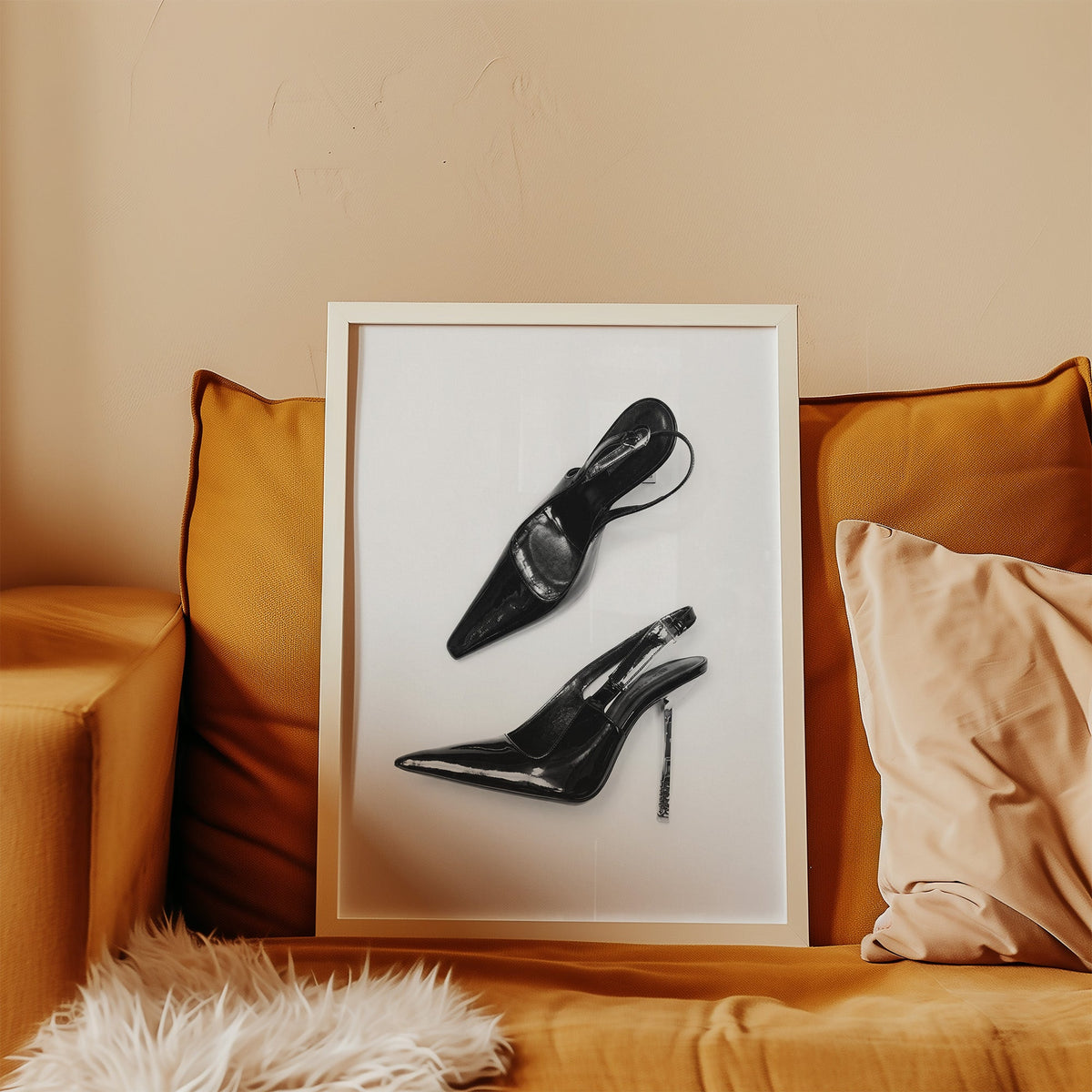 Black patent slingbacks with silver heels print in a white frame leaning on a mustard velvet sofa