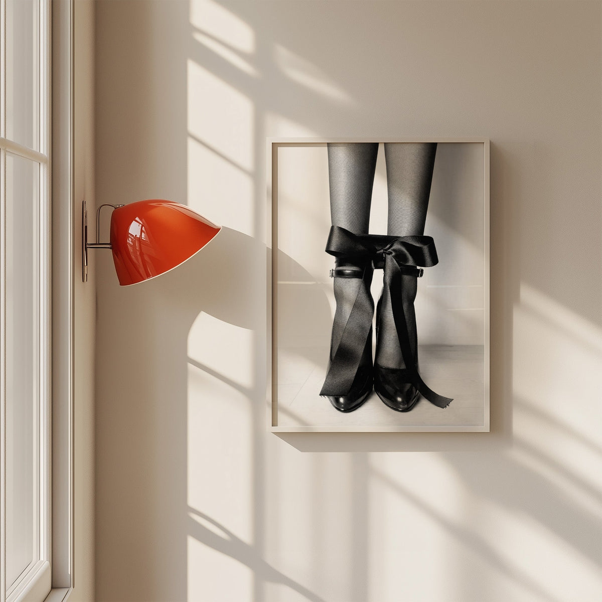 Heels with black satin bows tied at the ankle print in a white frame on a sunlit wall beside a red sconce