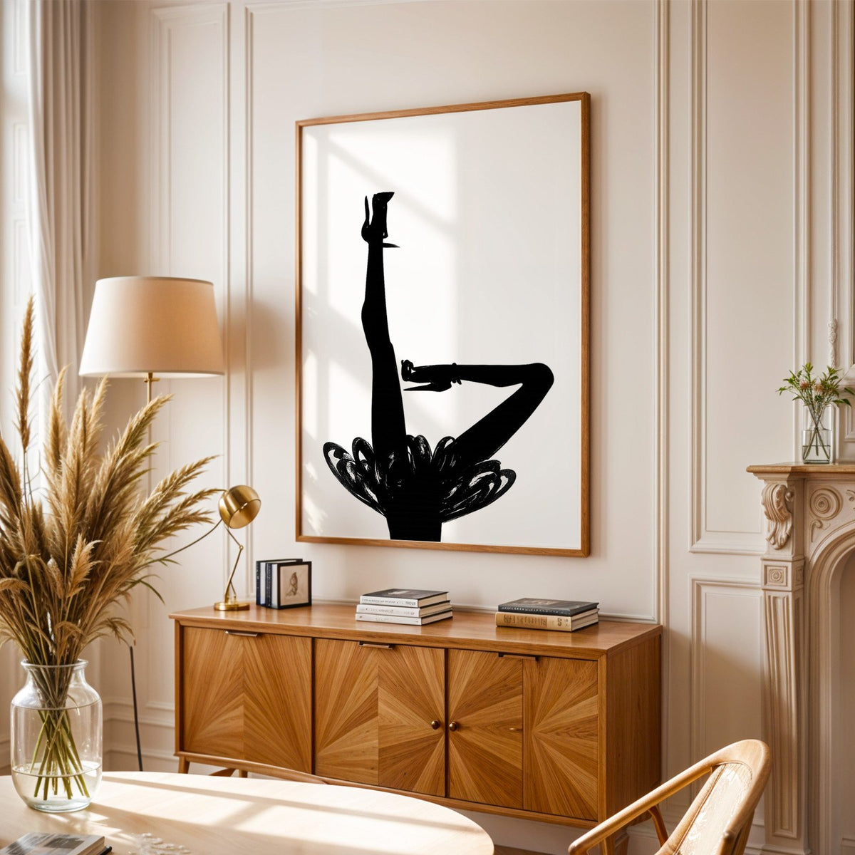 Black silhouette legs in heels with brushstroke skirt print in an oak frame above a sunburst wood sideboard with pampas grass