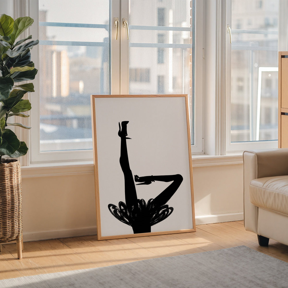 Black silhouette legs in heels with brushstroke skirt print in an oak frame leaning on the floor beside a fiddle leaf fig