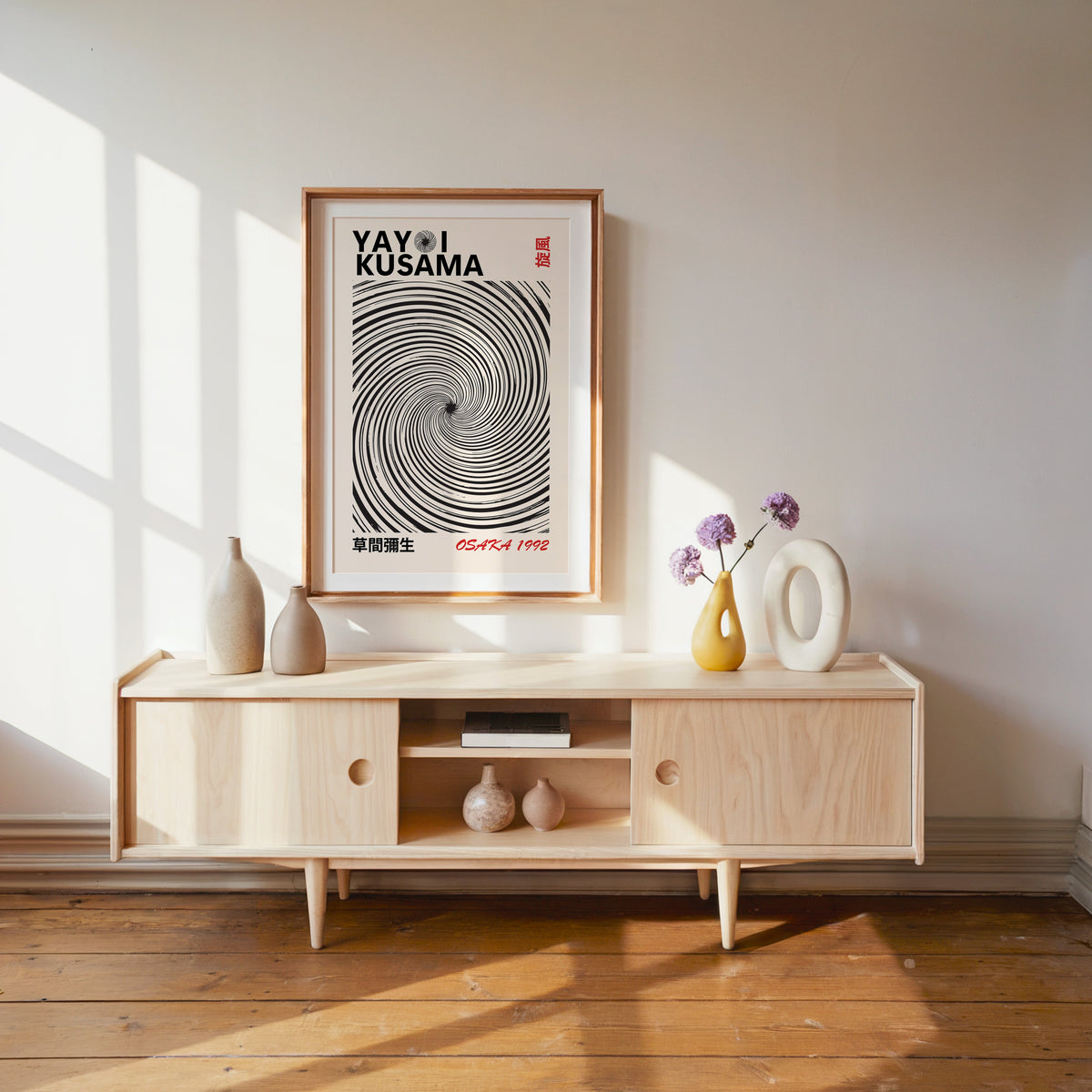 Yayoi Kusama inspired black spiral whirlwind print in a wood frame with white mat over a pale media console