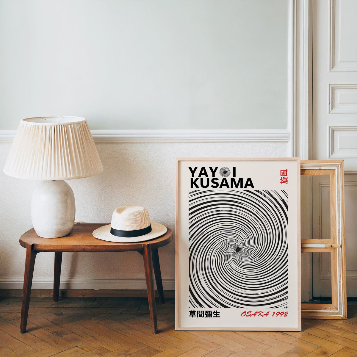 Yayoi Kusama inspired black spiral whirlwind print in an oak frame over a bench with a panama hat