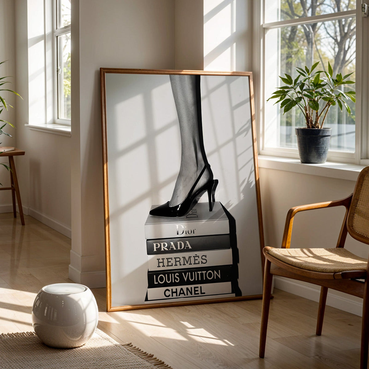 Glossy slingback heel standing on stacked books print in a walnut frame on a wood floor beside a cane chair and sunny window