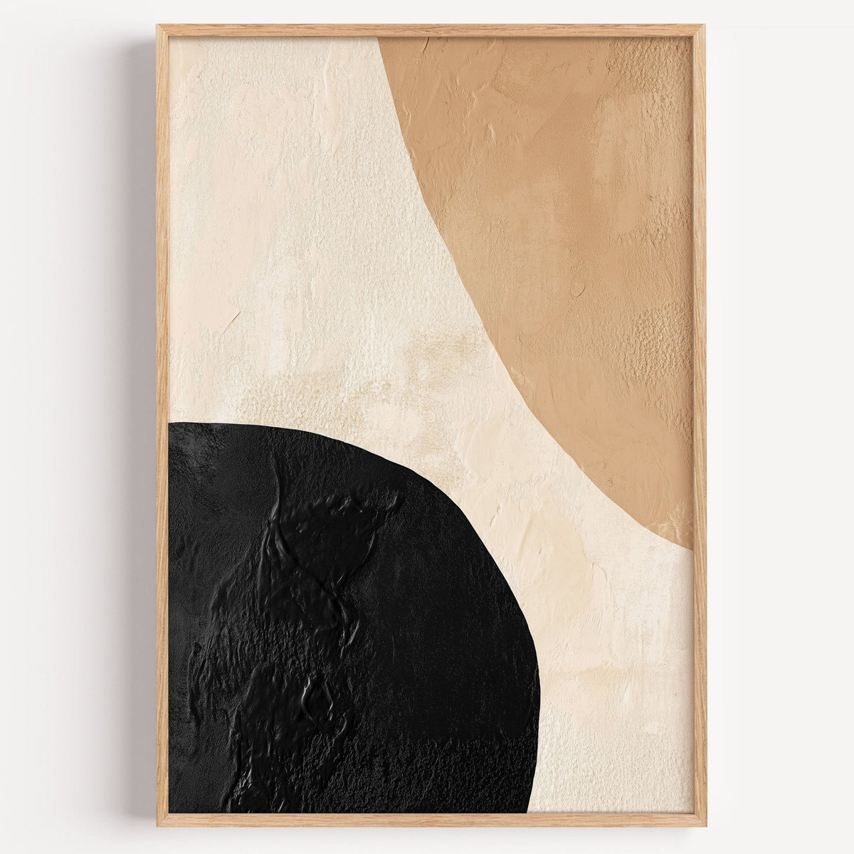 Black and tan textured shapes abstract print in a light oak frame on a plain white wall