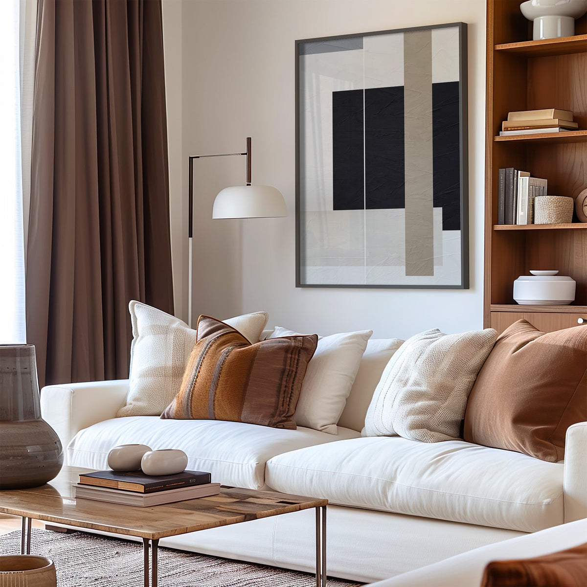 Black and taupe panels with thin lines print in a black frame above a cream sofa with brown striped pillows