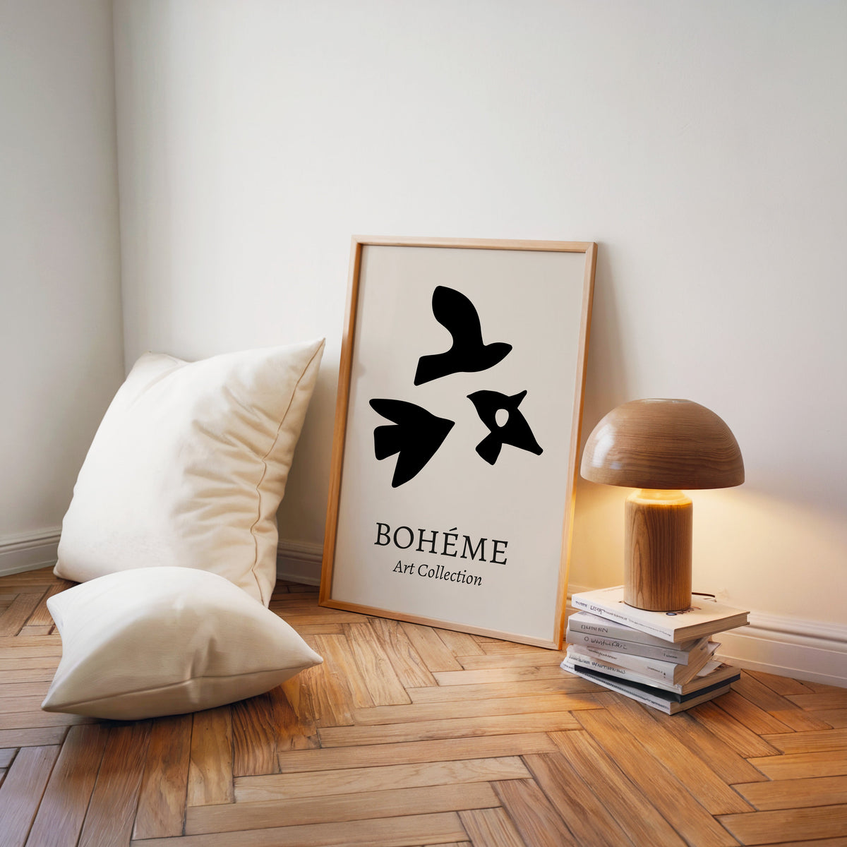 Black three birds cutout abstract print in a light wood frame on a herringbone floor by a wooden mushroom lamp