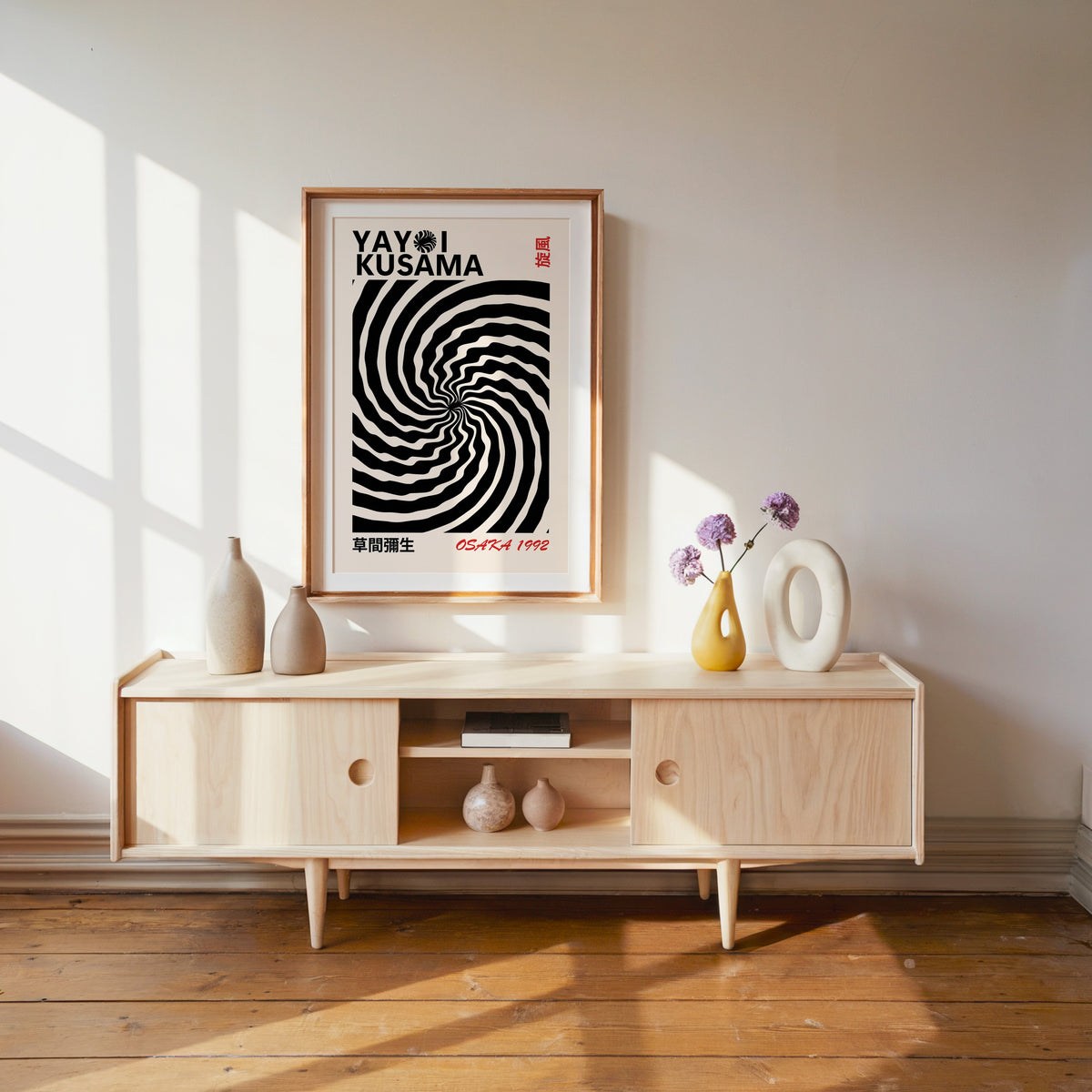 Yayoi Kusama inspired black wave swirl op art print in a wood frame with white mat over a pale media console
