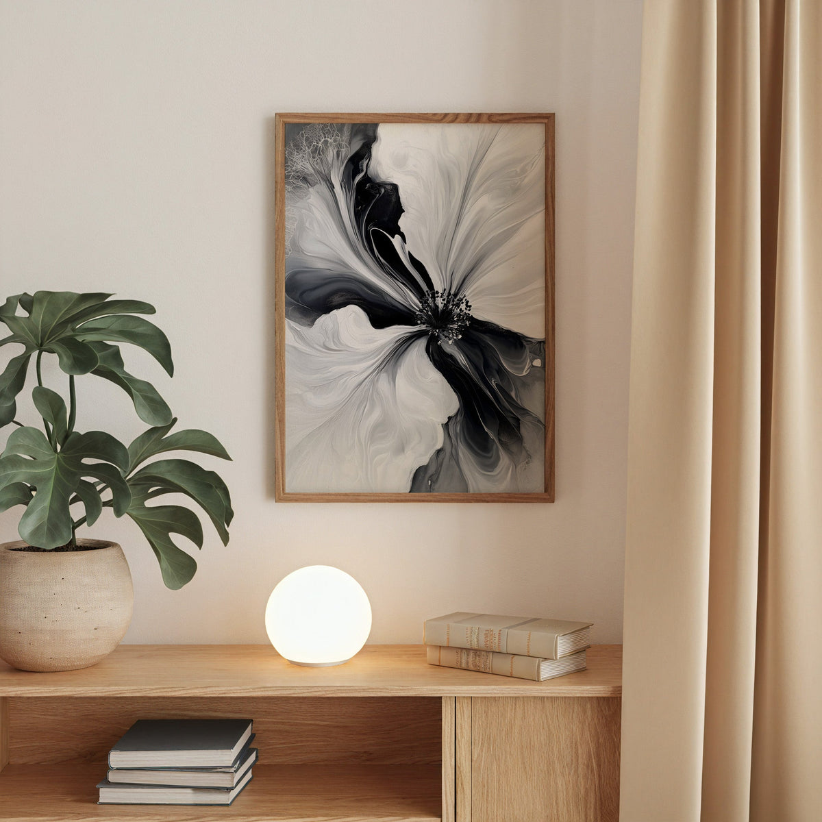Black and white fluid flower abstract print in a walnut frame above an oak cabinet with a glowing globe lamp