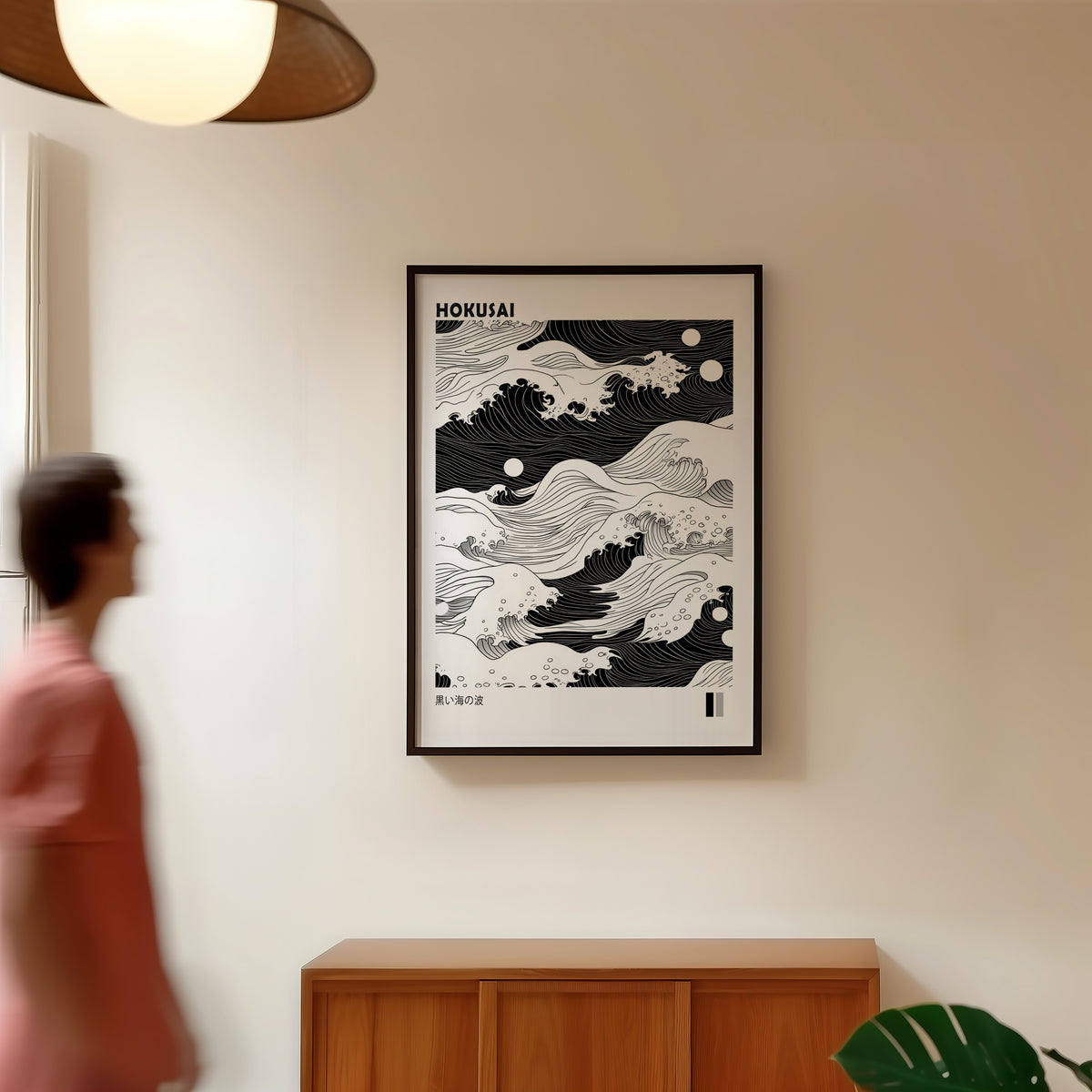 Black sea waves with twin moons print in a black frame in a hallway under a rattan pendant