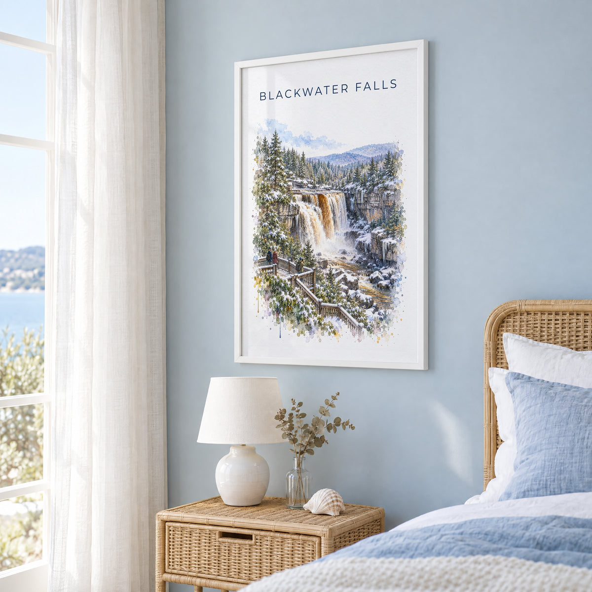 Blackwater Falls State Park watercolor print in a white frame on a pale blue wall beside a rattan bed in a coastal bedroom