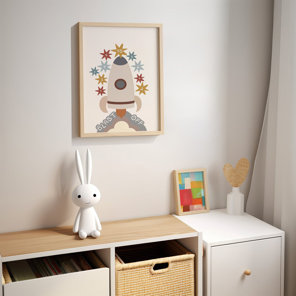 Blast off rocket countdown nursery print in an oak frame above a kids cubby shelf with a woven basket and bunny lamp