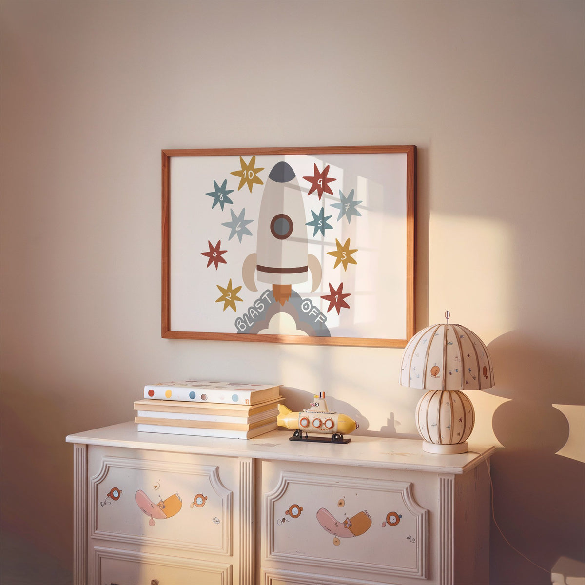Landscape blast off rocket countdown nursery print in a cherry wood frame above a painted dresser and lamp
