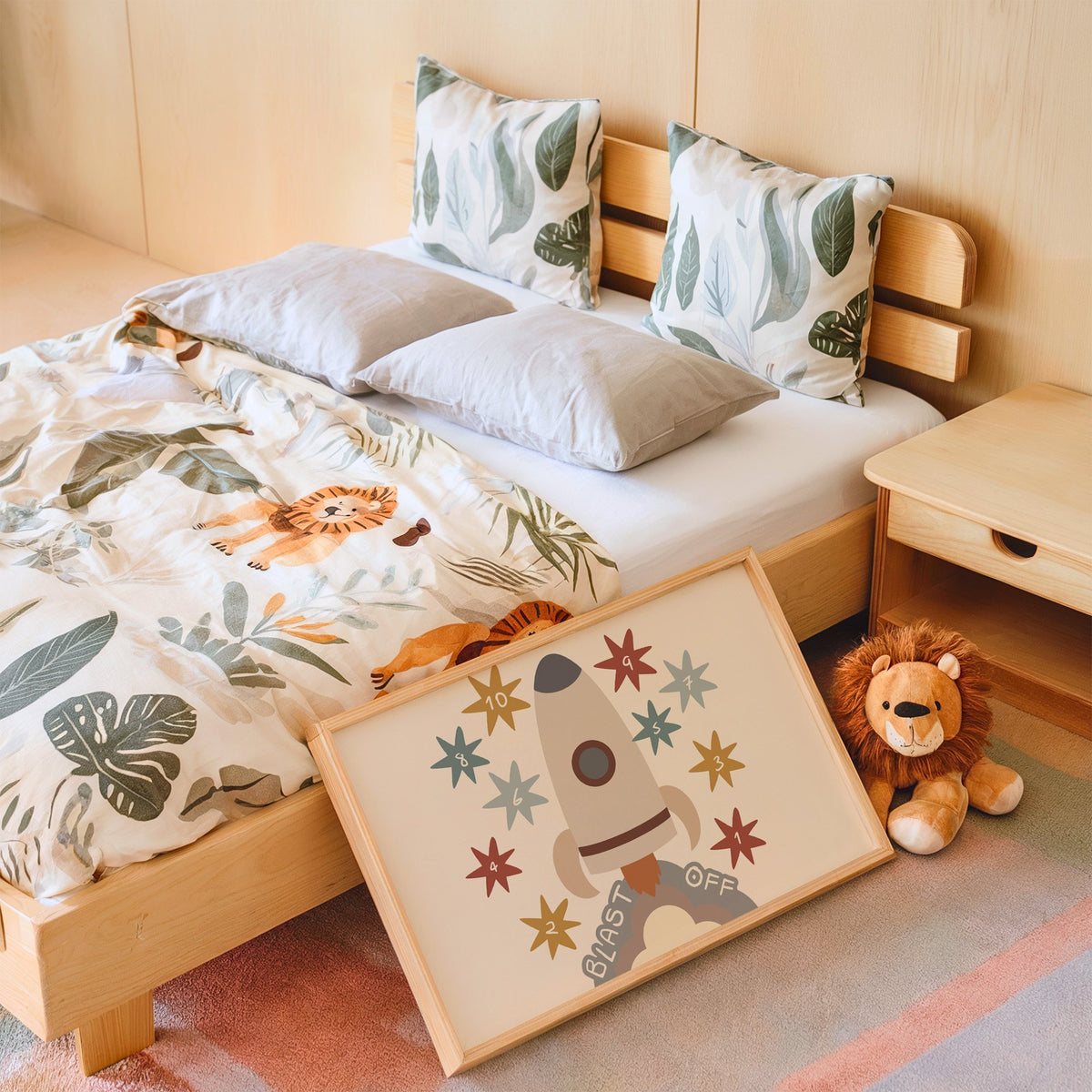 Landscape blast off rocket countdown nursery print in an oak frame leaning on a kids bed by a lion plush