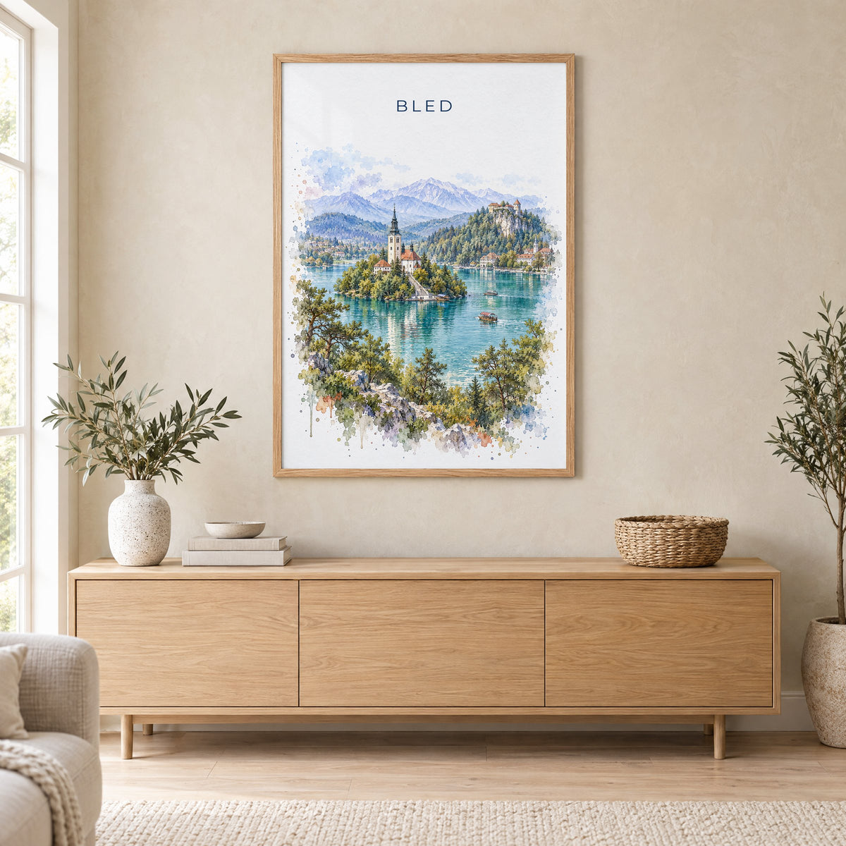 Bled watercolor print in an oak frame above a light wood sideboard in a Scandinavian living room