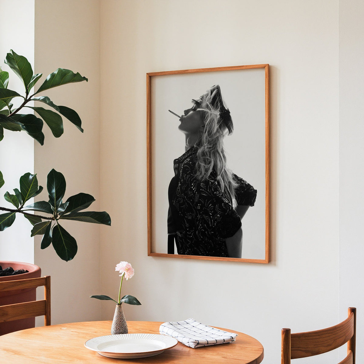 Backlit model in leather cap and sequin jacket print in a teak frame above a round wooden dining table