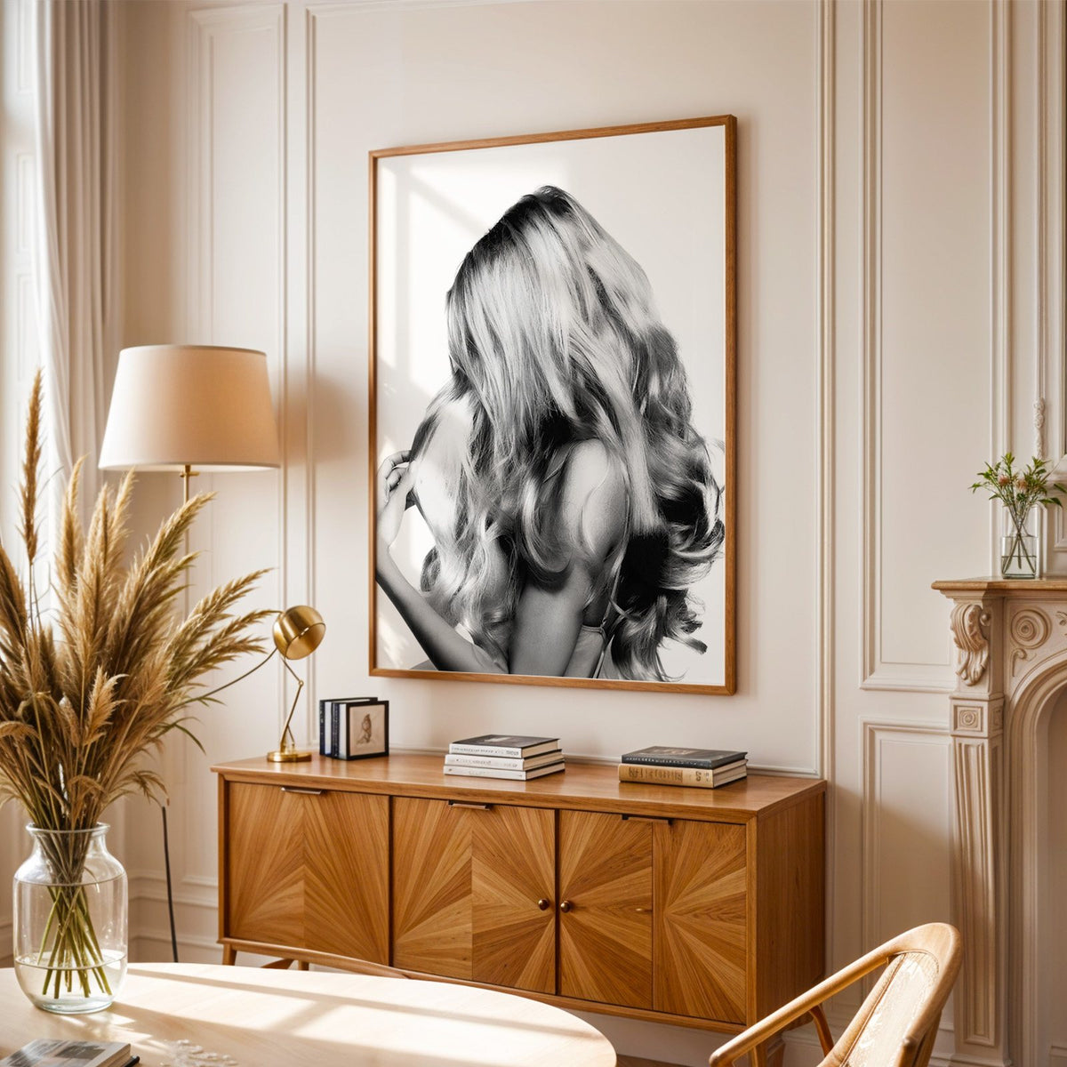 Long blonde wavy hair seen from behind print in an oak frame above a sunburst wood sideboard with pampas grass