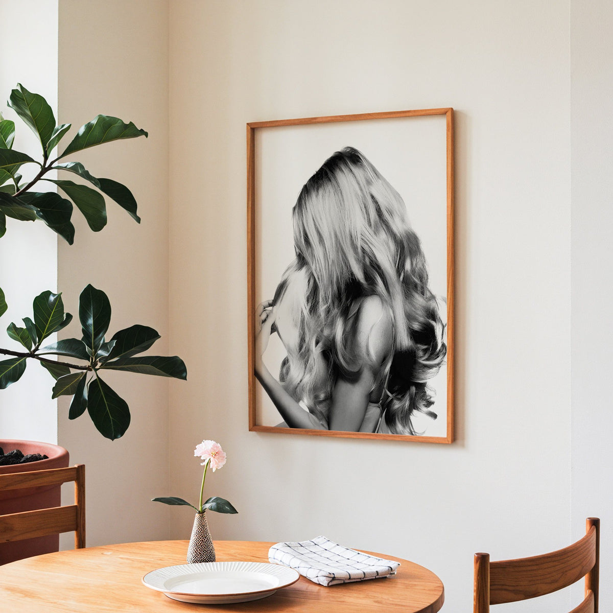 Long blonde wavy hair seen from behind print in a teak frame above a round wooden dining table