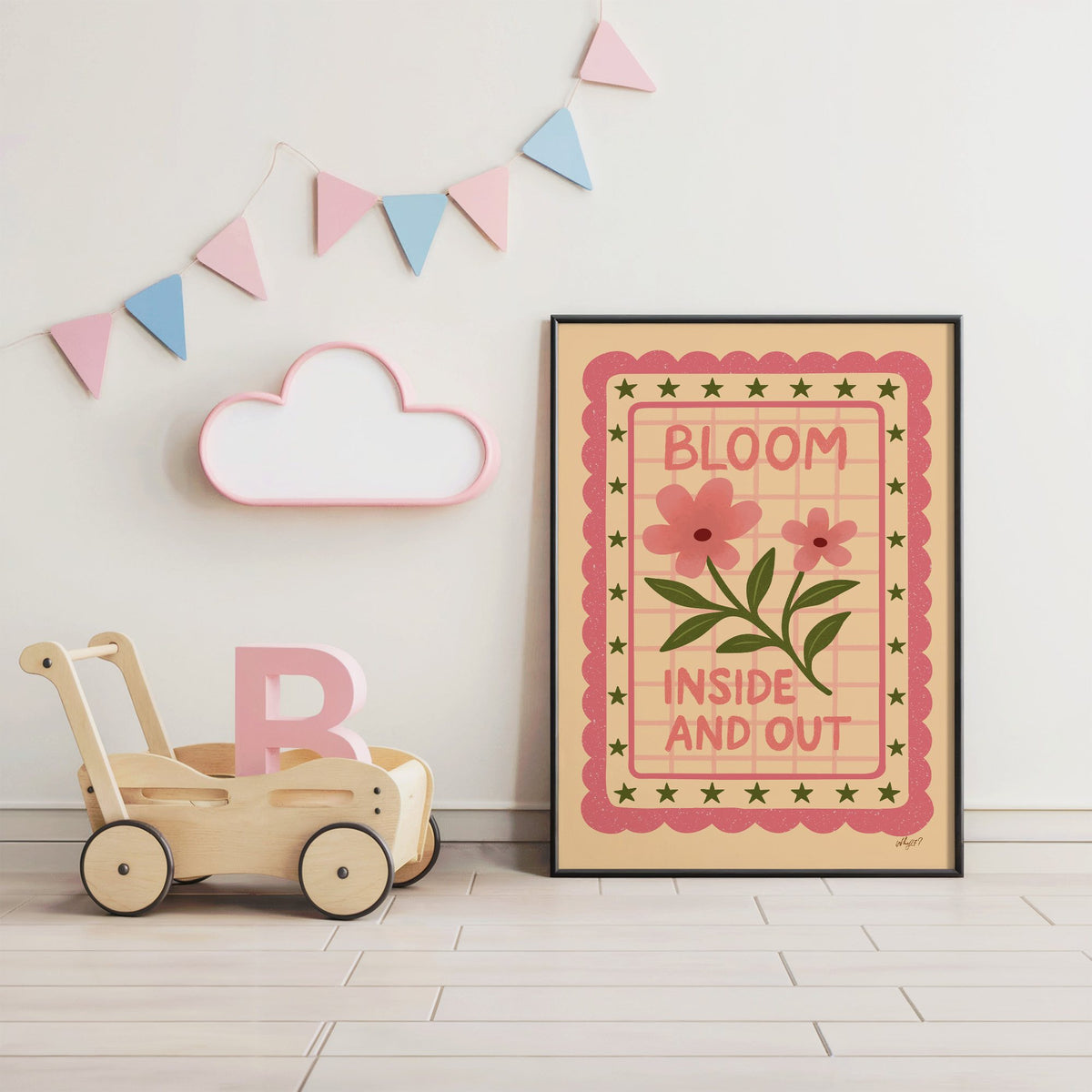 Bloom inside and out pink floral nursery print in a black frame under pastel bunting by a wooden baby walker