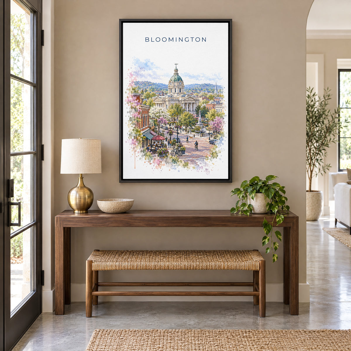 Bloomington, Indiana watercolor print as a black floater canvas above a walnut console and woven bench in an entryway