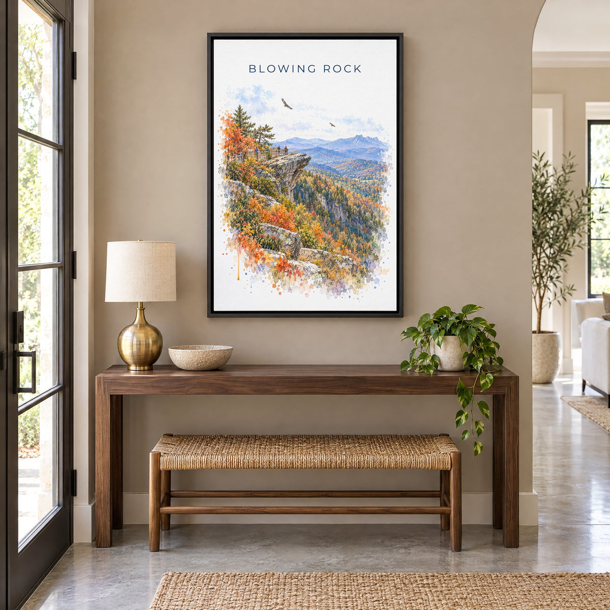 Blowing Rock watercolor print as a black floater canvas above a walnut console and woven bench in an entryway