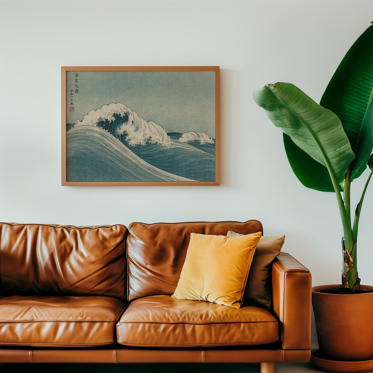 Blue crashing wave woodblock print in a warm oak frame above a cognac leather sofa with a mustard pillow