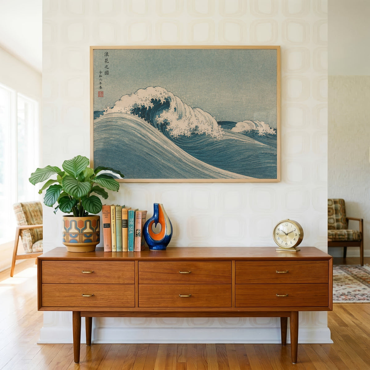 Blue crashing wave woodblock print in a light oak frame above a teak credenza with books and a brass clock