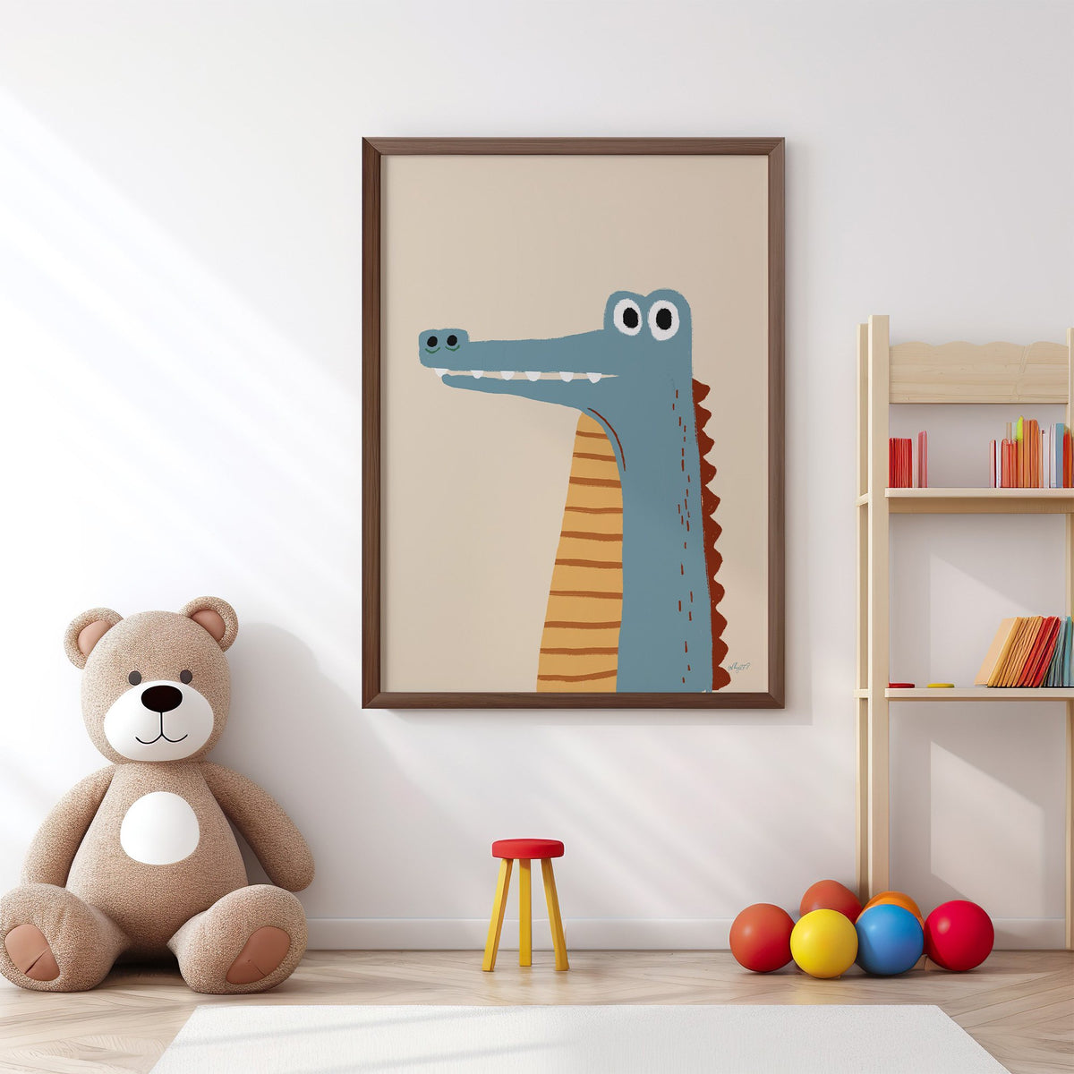Upright blue crocodile on cream nursery print in a walnut frame above a big teddy bear by a bookshelf