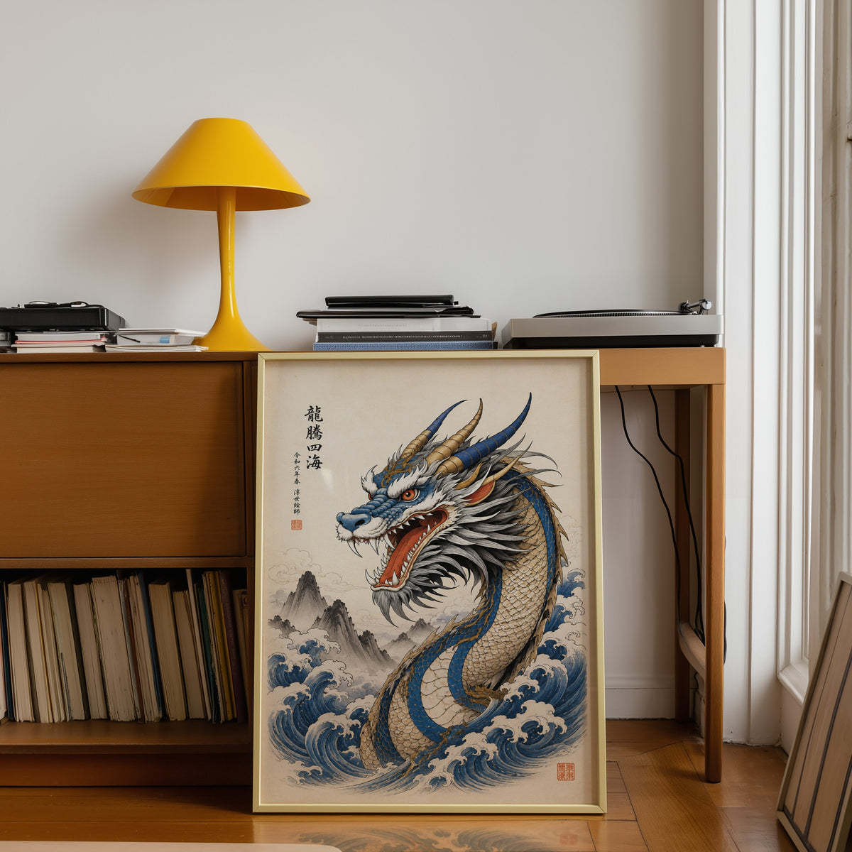 Blue dragon great waves poster shown in a gold frame leaning under a teak desk with a yellow lamp
