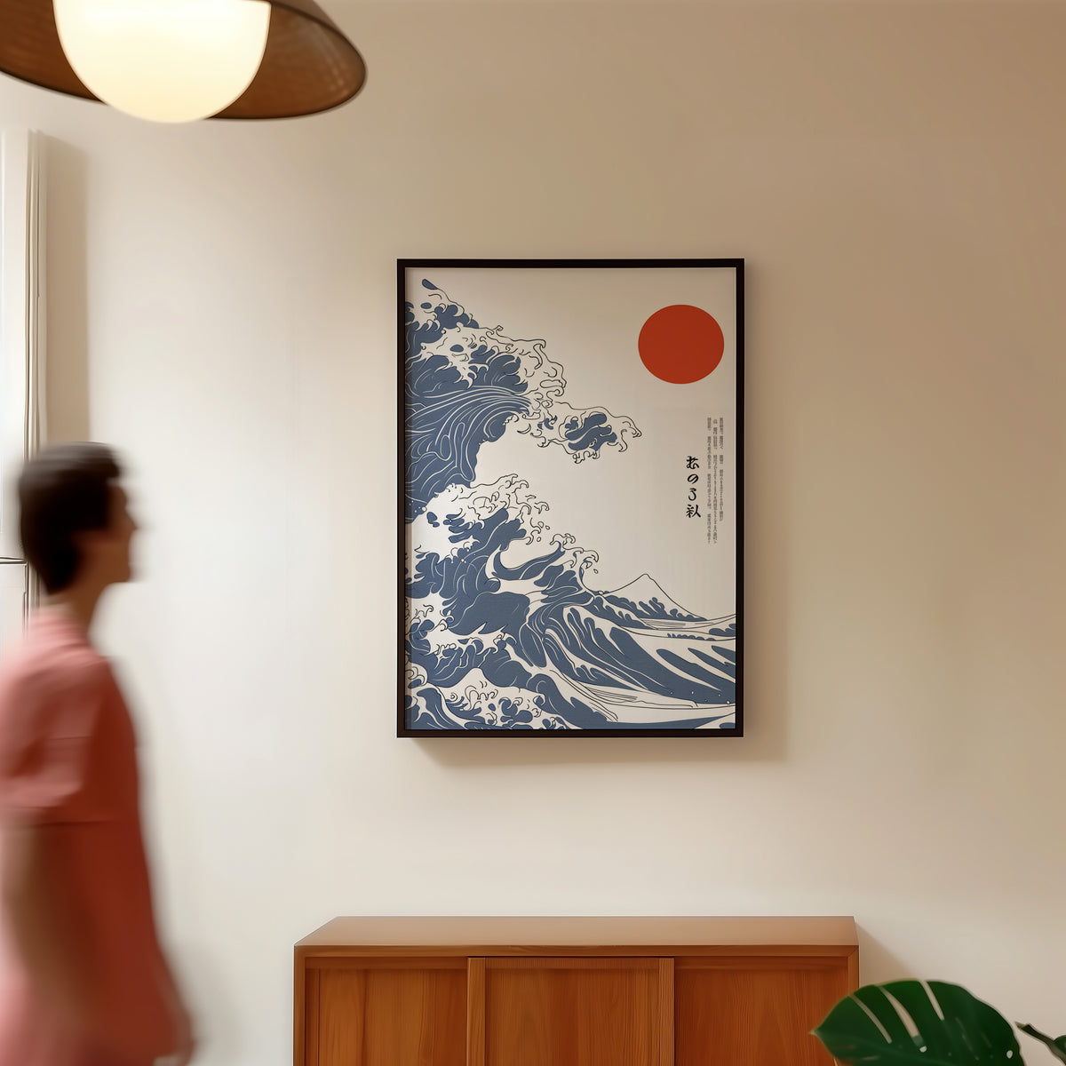Blue Great Wave with red sun print in a black frame in a hallway under a rattan pendant