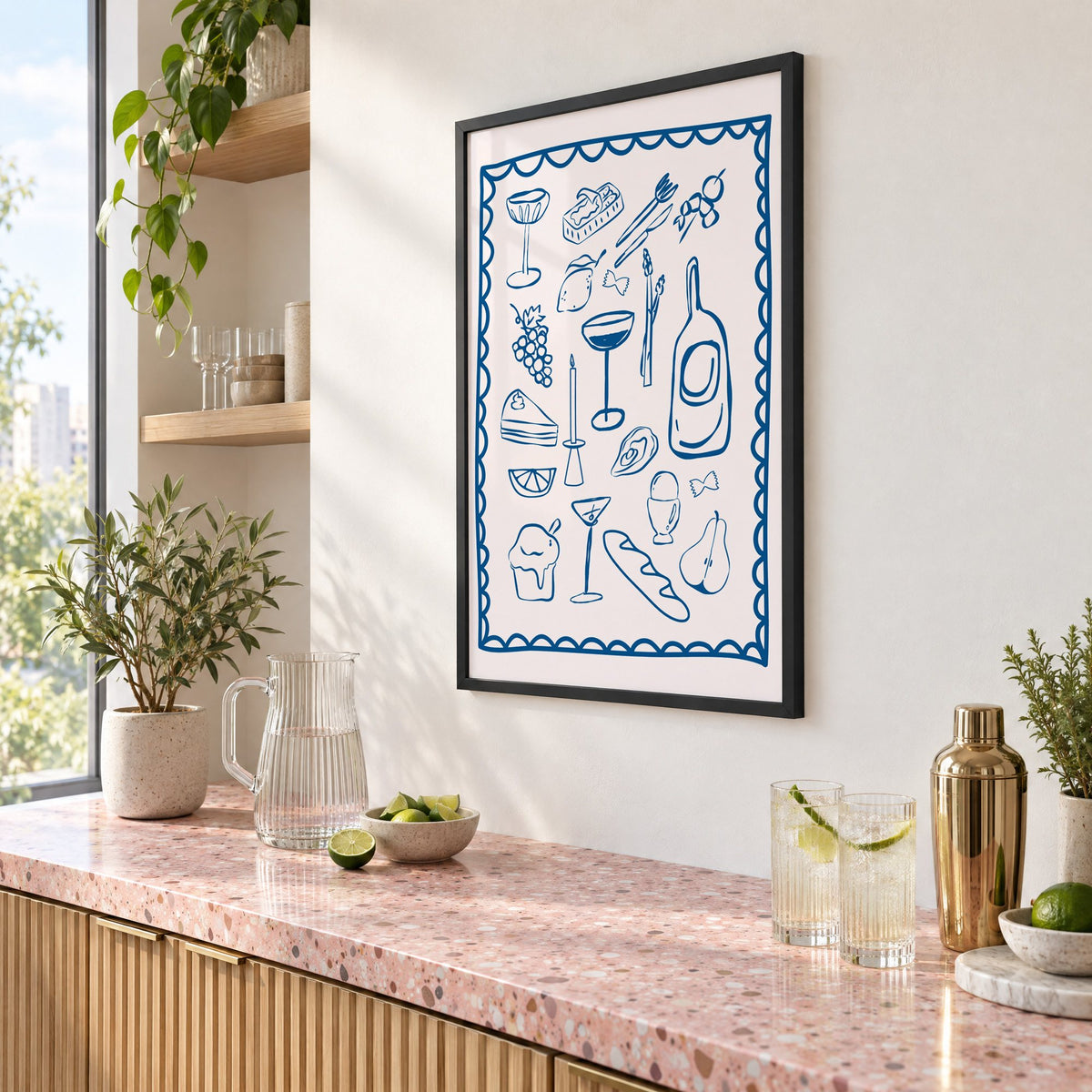 Blue line dinner party scalloped print in a black frame above a pink terrazzo cocktail counter with limes, seen at an angle