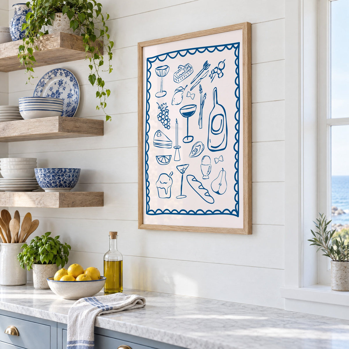 Blue line dinner party scalloped print in an oak frame in a white coastal kitchen beside blue and white plates