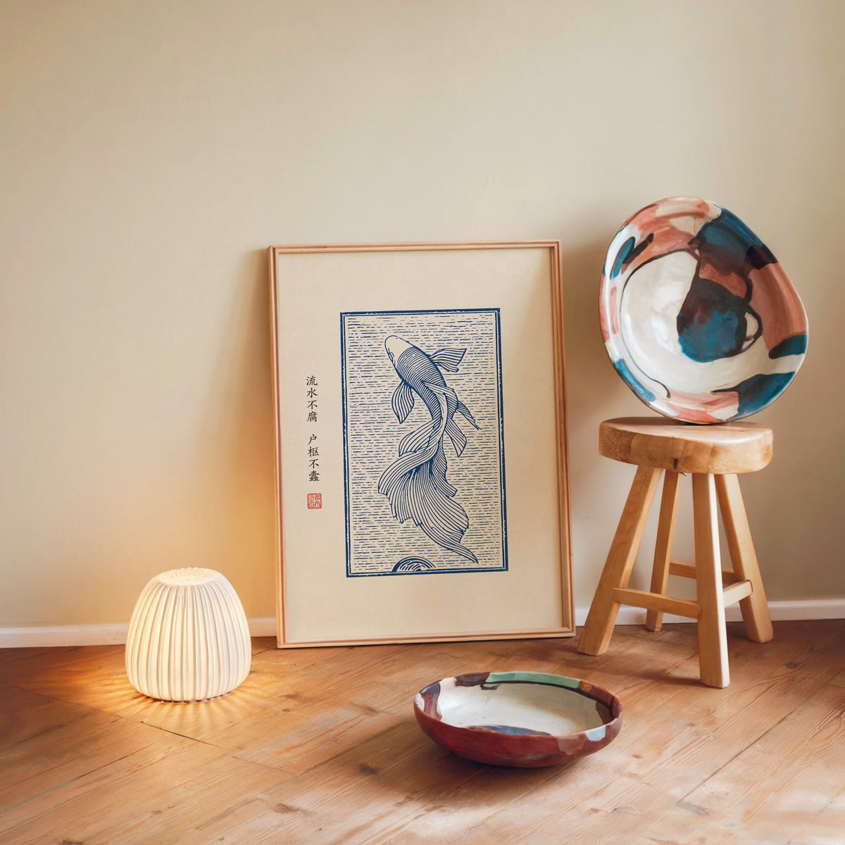 Blue line koi flowing water poster in a light wood frame leaning on a wooden floor by a glowing lamp and stool