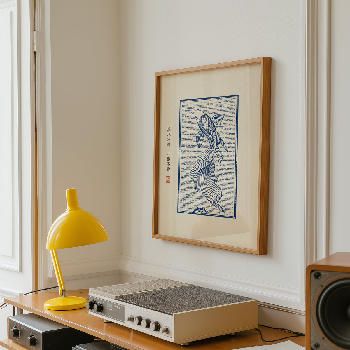 Blue line koi flowing water poster in an oak frame above a vintage hi-fi shelf with a yellow desk lamp