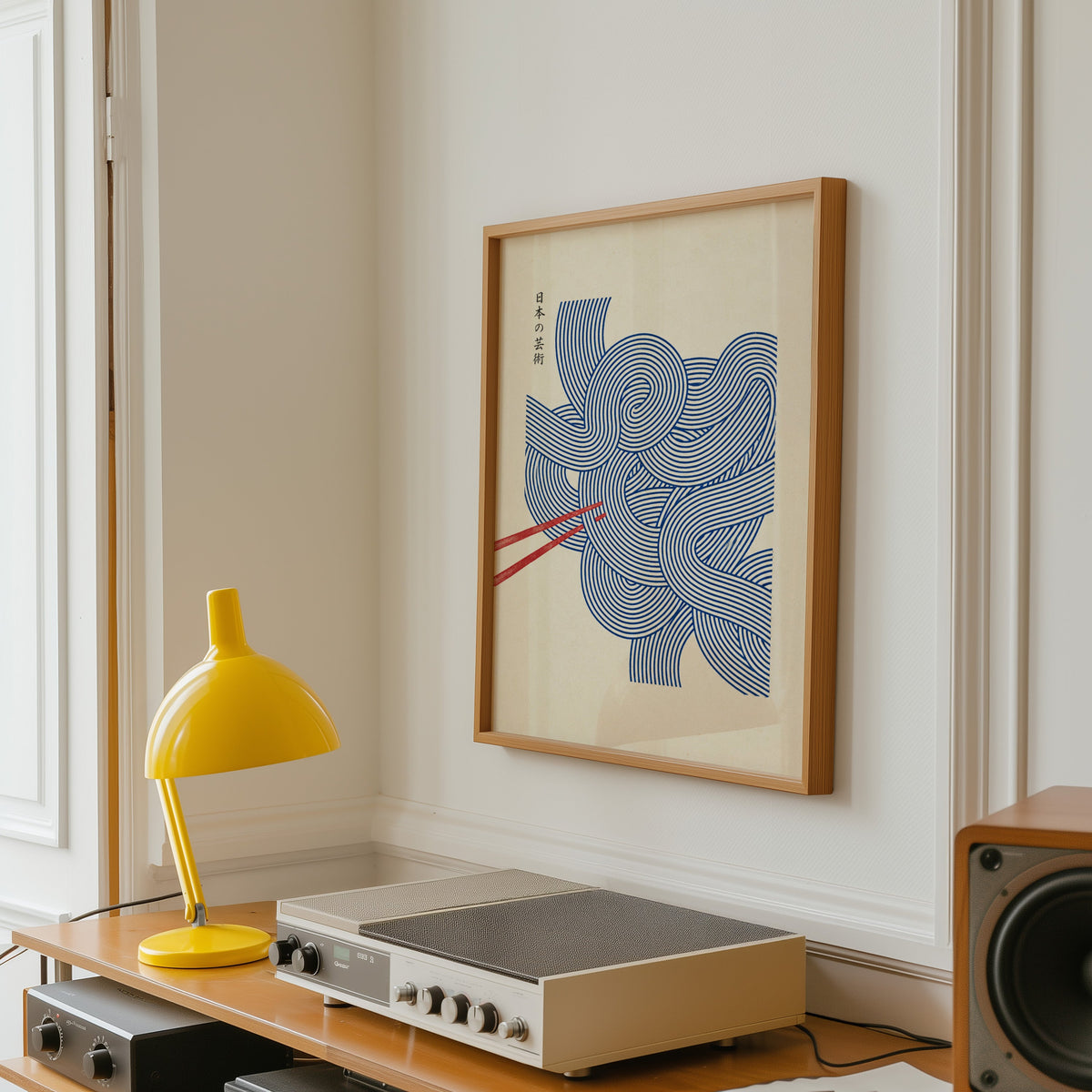Blue line noodles poster in an oak frame above a vintage hi-fi shelf with a yellow desk lamp