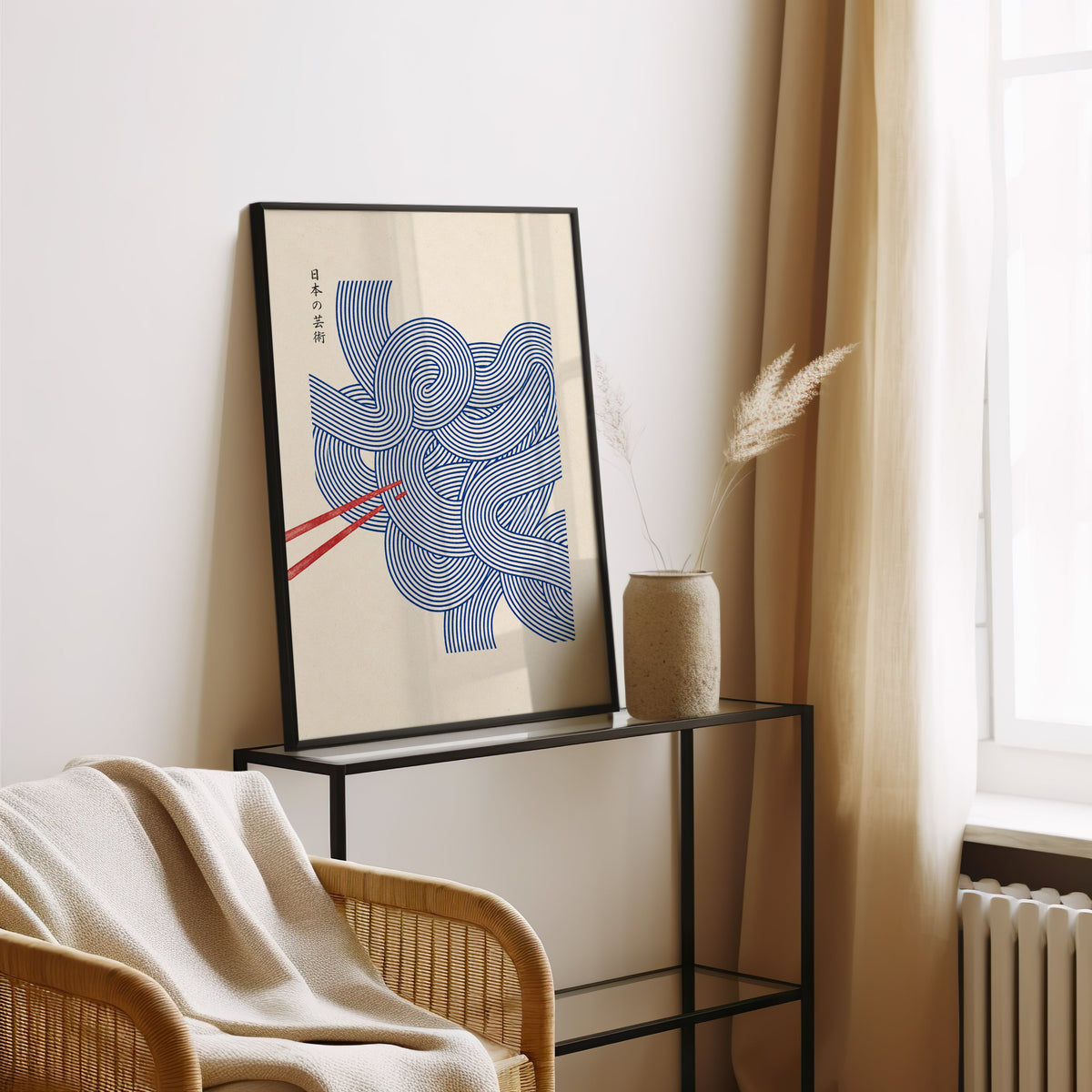 Blue line noodles poster in a black frame leaning on a glass console beside pampas grass
