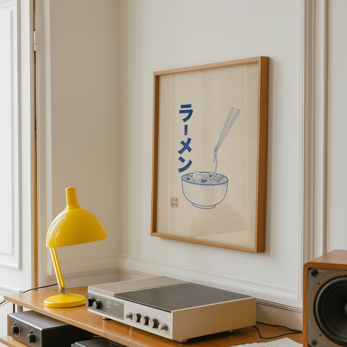Blue line ramen bowl poster in an oak frame above a vintage hi-fi shelf with a yellow desk lamp