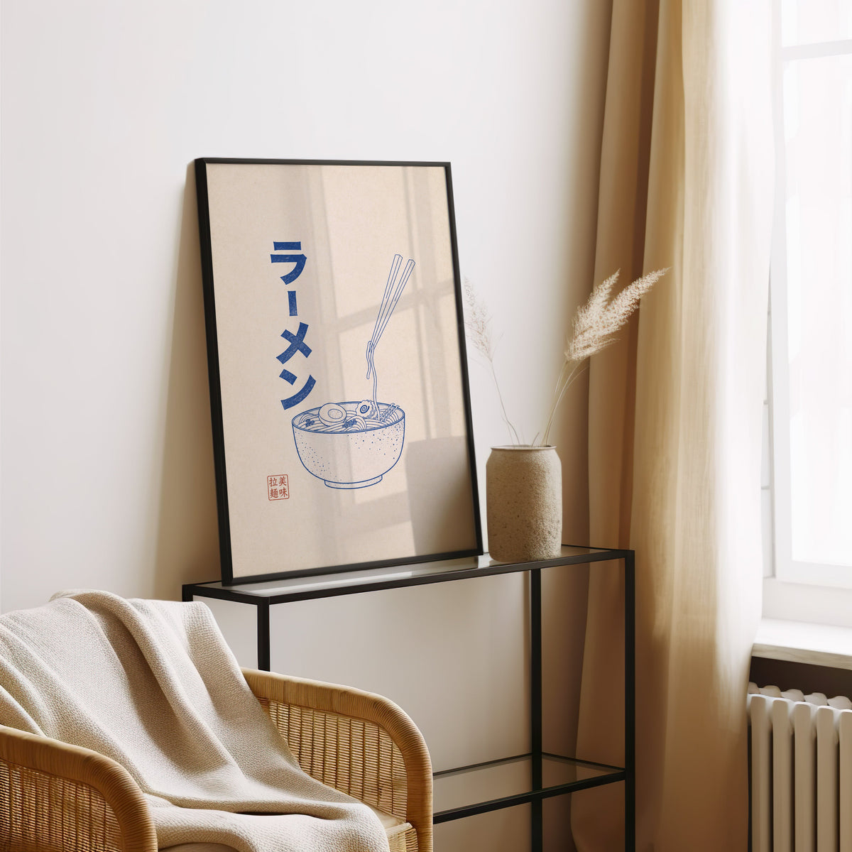 Blue line ramen bowl poster in a black frame leaning on a glass console beside pampas grass
